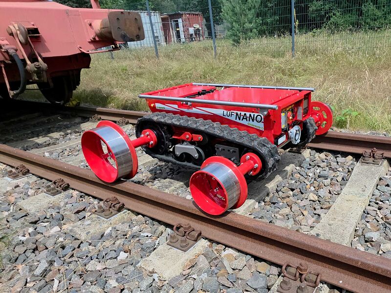 Ein ferngesteuerter Löschroboter mit Raupenfahrwerk und Schienenrädern steht auf einem Bahngleis.