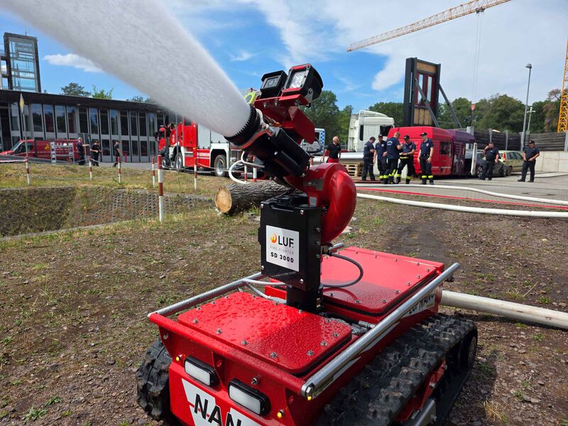 Ein ferngesteuerter Löschroboter sprüht über eine aufgesetzte Löschdüse Wasser nach vorne.